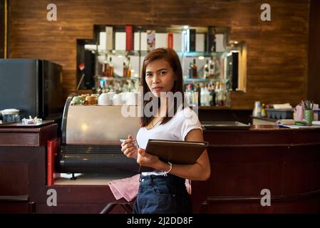 Tabelle für zwei Personen. Porträt einer freundlichen Kellnerin, die in einem thailändischen Restaurant auf die Gäste wartet. Stockfoto