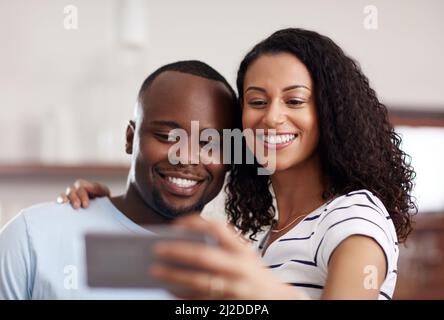 Erstes Selfie des Wochenendes. Ausgeschnittene Aufnahme eines jungen Ehepaares, das zu Hause in der Küche ein Selfie gemacht hat. Stockfoto