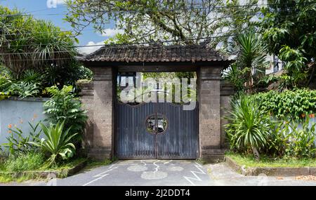 Alte Holztüren auf einer architektonischen Struktur mit Terrakotta-Lehm-Schindeldach in Bali Indonesien, umgeben von tropischen Pflanzen und Bäumen Stockfoto