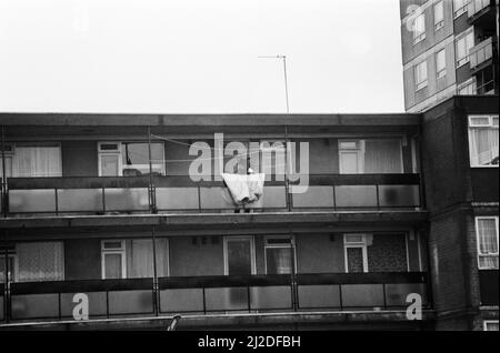 Errol Walker zwang sich am 25.. Dezember 1985 in eine Wohnung im dritten Stock des Poynter Court. Eine Frau taumelte aus und starb später an Messerstichen. Am folgenden Tag umzingelten bewaffnete Polizisten die Wohnungen, in denen Walker die vierjährige Carlene Charles als Geisel hatte. Auf dem Bild wird Carlene von Errol Walker vom Balkon der Wohnungen als Geisel gehalten, die bewaffnete Polizei belagerte darunter. 26.. Dezember 1985 Stockfoto