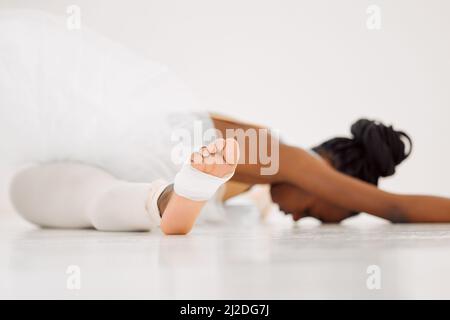 Seien Sie immer darauf vorbereitet. Aufnahme einer Tänzerin, die sich in einem Studio dehnt. Stockfoto