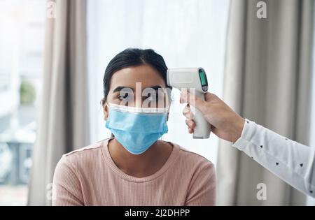 Lassen Sie uns überprüfen, ob Sie Fieber haben. Aufnahme eines nicht erkennbaren Arztes, der ein Thermometer verwendet, um die Temperatur eines Patienten in einem Büro zu messen. Stockfoto