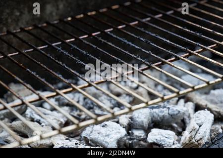 Glühende Holzkohle und Grillrost. Schmutziger Rost des Grills nach dem Kochen. Stockfoto