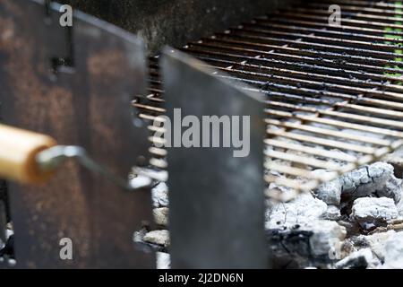 Glühende Holzkohle und Grillrost. Schmutziger Rost des Grills nach dem Kochen. Stockfoto