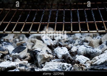 Glühende Holzkohle und Grillrost. Schmutziger Rost des Grills nach dem Kochen. Stockfoto