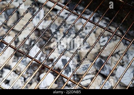 Glühende Holzkohle und Grillrost. Schmutziger Rost des Grills nach dem Kochen. Stockfoto