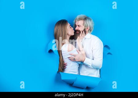 Paar in Liebe Kuss in Loch Papier Hintergrund. Rabatt und Verkauf. Geküsste Paar bärtige Mann und glückliche Frau machen Loch in Papier Kuss durch Loch Stockfoto