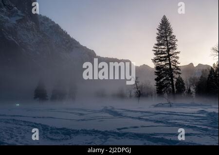 Das Yosemite Valley ist von einer dünnen Nebelschicht umgeben, die über dem merced River hängt und eine unheimliche Atmosphäre beim Sonnenuntergang bietet. Stockfoto