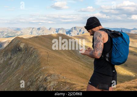 Wanderführer beim Überprüfen der RoutenApp auf dem Smartphone auf dem Otovitsa-Gipfel bei 2697m auf dem Europäischen Fernwanderweg E4, Rila-Berg, Bulgarien Stockfoto