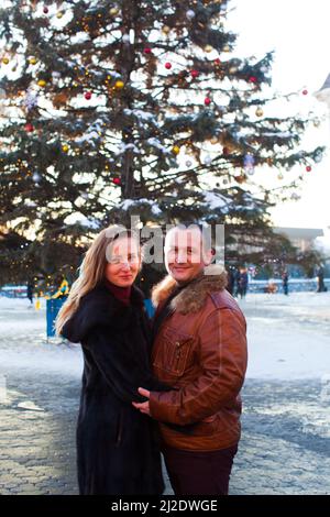 Das schöne Paar steht am Hintergrund des Weihnachtsbaums in der Stadt Stockfoto