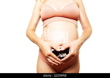 Der Bauch einer Schwangeren hält die Hände in Herzform Stockfoto