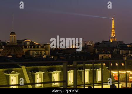 Blick auf den beeindruckenden beleuchteten Eiffelturm über den Dächern von Paris Stockfoto