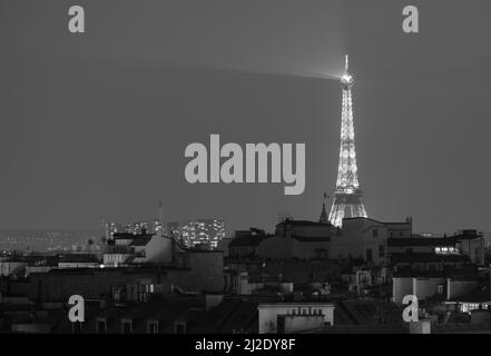 Blick auf den beeindruckenden beleuchteten Eiffelturm über den Dächern von Paris in Schwarz und Weiß Stockfoto