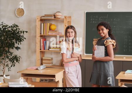 Porträt von zwei lächelnden Schülerinnen, die im Klassenzimmer auf die Kamera blicken und Platz kopieren Stockfoto