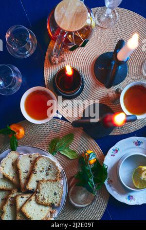 Festliche Stillleben von Tee, Kuchen, Mandarinen und Kerzen. Heiligabend und Silvester. Flach liegend. Stockfoto