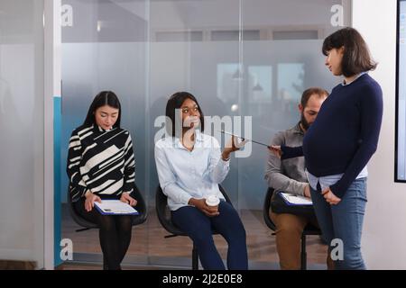 Personalabteilung schwanger Teamleiter geben afroamerikanische Frau Beschäftigung Form Zwischenablage während der Wartezeit in Lobby-Bereich. HR-Manager im Gespräch mit dem Kandidaten über die Stellenbeschreibung. Stockfoto