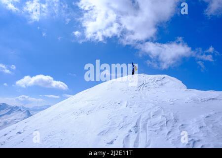 Skibergsteiger, der die Spitze eines Berges in der Schweiz erreicht Stockfoto