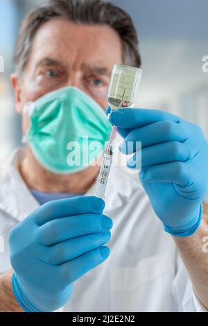 Der Arzt füllt eine Spritze mit Impfstoff auf verschwommenem Hintergrund. Stockfoto