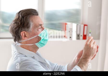 Der Arzt füllt eine Spritze mit Impfstoff auf verschwommenem Hintergrund. Stockfoto