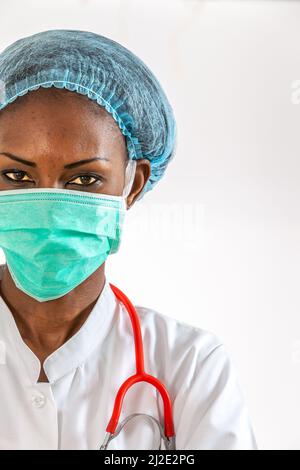 Weibliche amerikanische afrikanische Ärztin, Krankenschwester Frau trägt medizinischen Mantel, Kappe, mit Stethoskop und Maske. Stockfoto