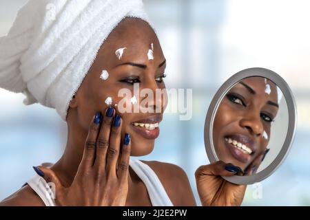 Junge Frau vor einem Badezimmerspiegel, der Creme auf einen roten Noppen setzt. Beauty-Hautpflege und Wellness-Morgenkonzept. Stockfoto