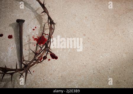 Osterkonzept. Dornenkrone mit Nagel und Bluttropfen auf einem steinernen Hintergrund. Stockfoto