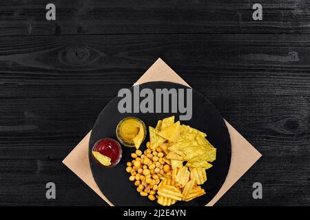 Große Auswahl an Snacks für Bier mit verschiedenen Saucen auf Pergament Draufsicht Stockfoto