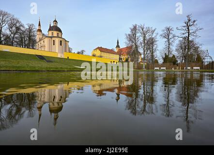 01. April 2022, Brandenburg, Neuzelle: Blick aus dem Klostergarten der evangelischen (l) und katholischen (r) Kirchen des Klosters Neuzelle. Im Klostergarten Neuzelle in der oder-Spree werden seit rund zwei Jahren die dritte und letzte Bauphase zur Sanierung des Barockgeländes durchgeführt. Hier entstehen eine Baumschule mit Gewächshaus, Küchengarten und Kräutergarten sowie symmetrisch angelegte Blumenbeete, die mit Hecken und Obstbäumen gesäumt sind. Seit 1998 wird an der knapp 5 Hektar großen Gartenanlage gearbeitet, die das einzige barocke G ist Stockfoto