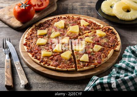 Hawaiianische Pizza mit Ananas, Schinken und Käse auf einem Holztisch Stockfoto