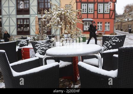 Wernigerode, Deutschland. 01. April 2022. Die Tische und Stühle des Straßencafés sind mit Schnee bedeckt. Es gibt Schnee bis in die Tiefebene der Region. Weitere Schneeschauer werden in den kommenden Tagen erwartet. Quelle: Matthias Bein/dpa - ACHTUNG: Das Nummernschild wurde aus Datenschutzgründen verpixelt./dpa/Alamy Live News Stockfoto