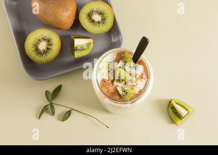 Blick von oben auf ein Glas hausgemachten frisch zubereiteten Kiwi-, Bananen- und Nusssmoothies. Tolles gesundes Frühstück oder Snack. Pastellhintergrund Stockfoto