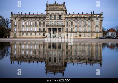 Ludwigslust, Deutschland. 01. April 2022. Schloss Ludwigslust, auch bekannt als das "Versailles des Nordens", spiegelt sich im Wasser der Großen Kaskade wider. Das zweiflügelige Wohnhaus, das von 1772 bis 1776 nach Plänen des Hofarchitekten Johann Joachim Busch erbaut wurde, wird derzeit an der Westseite umfassend renoviert. Nach zwölf Millionen Euro Baumaßnahmen soll das Museum 2024 wieder für Besucher geöffnet werden. Quelle: Jens Büttner/dpa/Alamy Live News Stockfoto