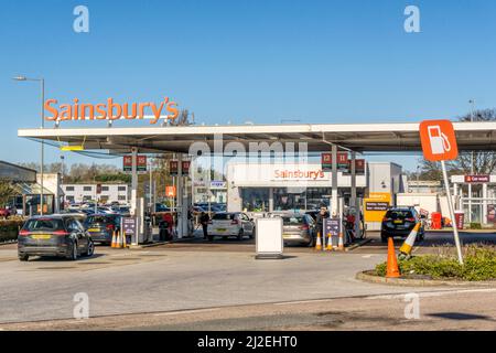 Autos, die sich auf dem Vorplatz einer Tankstelle in einem Sainsbury's Supermarkt den Zapfsäulen nähern. Stockfoto