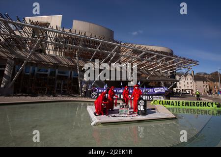 Edinburgh, Schottland, 1. April 2022. Klimaaktivisten vom Aussterben Rebellion protestieren vor dem schottischen Parlament am Tag der Rekordanstiege der Energiepreise in Großbritannien. Aktivisten, von denen einer eine Maske des russischen Präsidenten Wladimir Putin trug, inszenierten vor dem Gebäude einen Ölpest, um gegen die anhaltende Abhängigkeit von fossilen Brennstoffen zu protestieren. Foto: Jeremy Sutton-Hibbert/Alamy Live News. Stockfoto