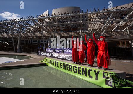 Edinburgh, Schottland, 1. April 2022. Klimaaktivisten vom Aussterben Rebellion protestieren vor dem schottischen Parlament am Tag der Rekordanstiege der Energiepreise in Großbritannien. Aktivisten, von denen einer eine Maske des russischen Präsidenten Wladimir Putin trug, inszenierten vor dem Gebäude einen Ölpest, um gegen die anhaltende Abhängigkeit von fossilen Brennstoffen zu protestieren. Foto: Jeremy Sutton-Hibbert/Alamy Live News. Stockfoto