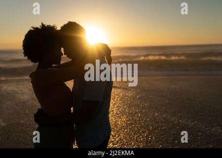 Romantisches afroamerikanisches Paar, das während des Sonnenuntergangs gemeinsam am Strand Freizeit verbringt Stockfoto