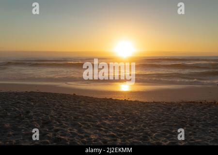 Idyllische Aufnahme von orangefarbenem Sonnenuntergang über dem Meer vom Strand aus gesehen Stockfoto