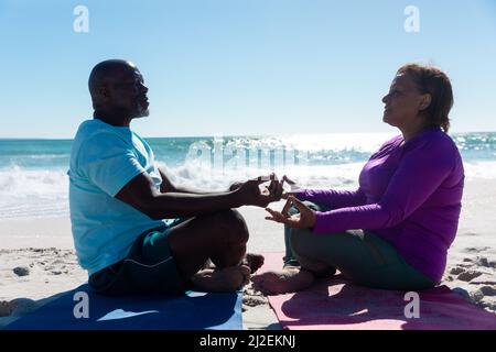 afroamerikanisches Seniorenpaar meditiert während des Yoga-Übens am Strand an sonnigen Tagen Stockfoto