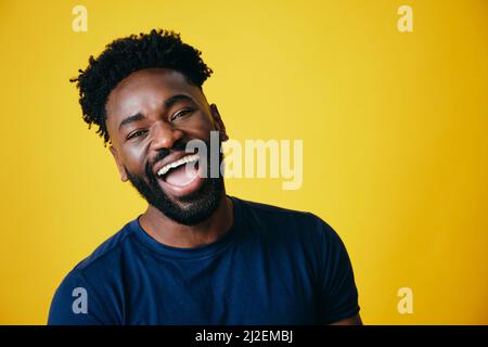 Porträt eines verspielten Afro-Mannes mit offenem Mund vor gelbem Hintergrund Stockfoto