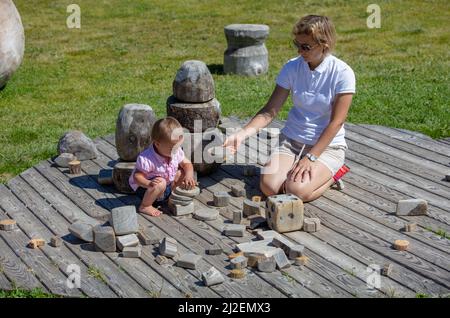 Mutter und ihr 18 Monate altes Kleinkind spielen mit Holzschnitten, Blöcken, Würfeln und anderem in der Sonne und an der frischen Luft rund um die Seiser Alm, Südtirol, Italien Stockfoto