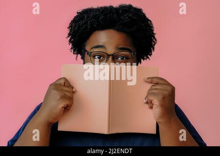 afroamerikanischer Mann posiert mit einem Buch im Studio über einem männlichen Model mit rosa Hintergrund Stockfoto