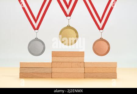 Plattform aus Holzblöcken und goldenen Silber- und Bronzemedaillen als Symbol der ersten zweiten und dritten Sieger. Stockfoto