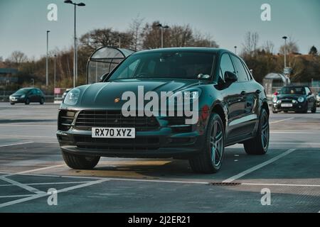 Die Seitenaufnahme eines schwarzen Porsche Cayman auf einem Parkplatz Stockfoto
