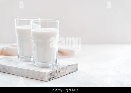 Zwei Gläser Milch auf einem Holzbrett auf hellem Hintergrund. Stockfoto