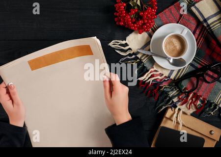 Smartphone und Kaffeetasse, Lesebrille, Notebook, Hände halten Zeitung. Stockfoto