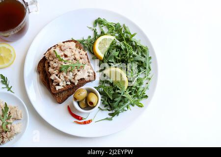 Scheiben Vollkornbrot mit Thunfisch, Zitrone und Gemüse isoliert auf weißem Hintergrund. Thunfisch-Vorspeise. Direkt darüber. Stockfoto