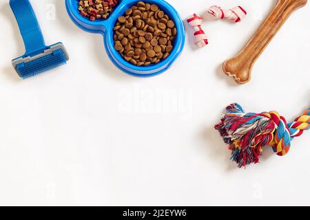 Hundepflegeartikel, isoliert auf weißem Hintergrund. Tierfutter in Schale, Spielzeug und Knochen trocknen. Draufsicht Stockfoto