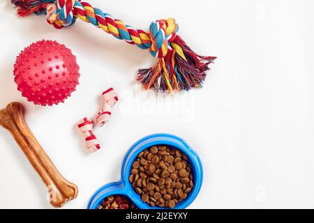 Trockenes Tierfutter in Schale und Spielzeug für Hunde auf weißem Hintergrund Draufsicht Stockfoto