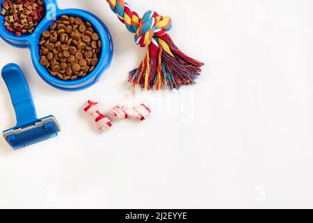 Hundepflegeartikel, isoliert auf weißem Hintergrund. Tierfutter in Schale, Spielzeug und Knochen trocknen. Draufsicht Stockfoto