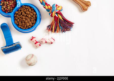 Hundepflegeartikel, isoliert auf weißem Hintergrund. Tierfutter in Schale, Spielzeug und Knochen trocknen. Draufsicht Stockfoto
